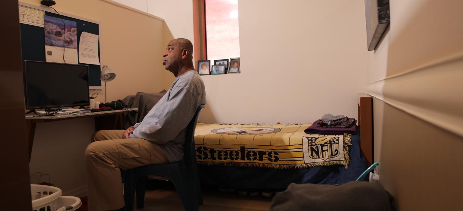 Shelter and Transitional Housing Header Man sitting in a room looking off in the distance