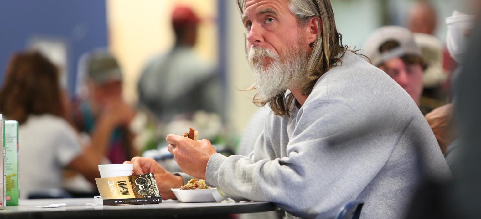 Dining Room Header Man eating food looking off into the distance