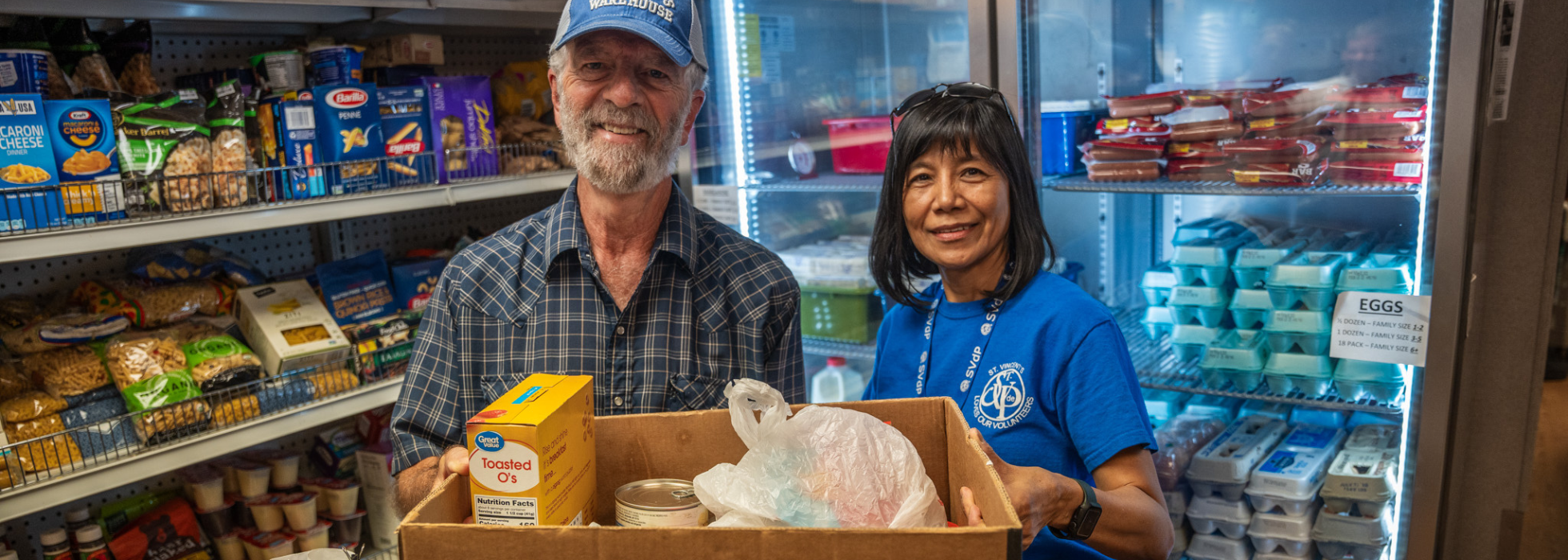 food-box-campaign-header Man and woman holding a food box in a food pantry
